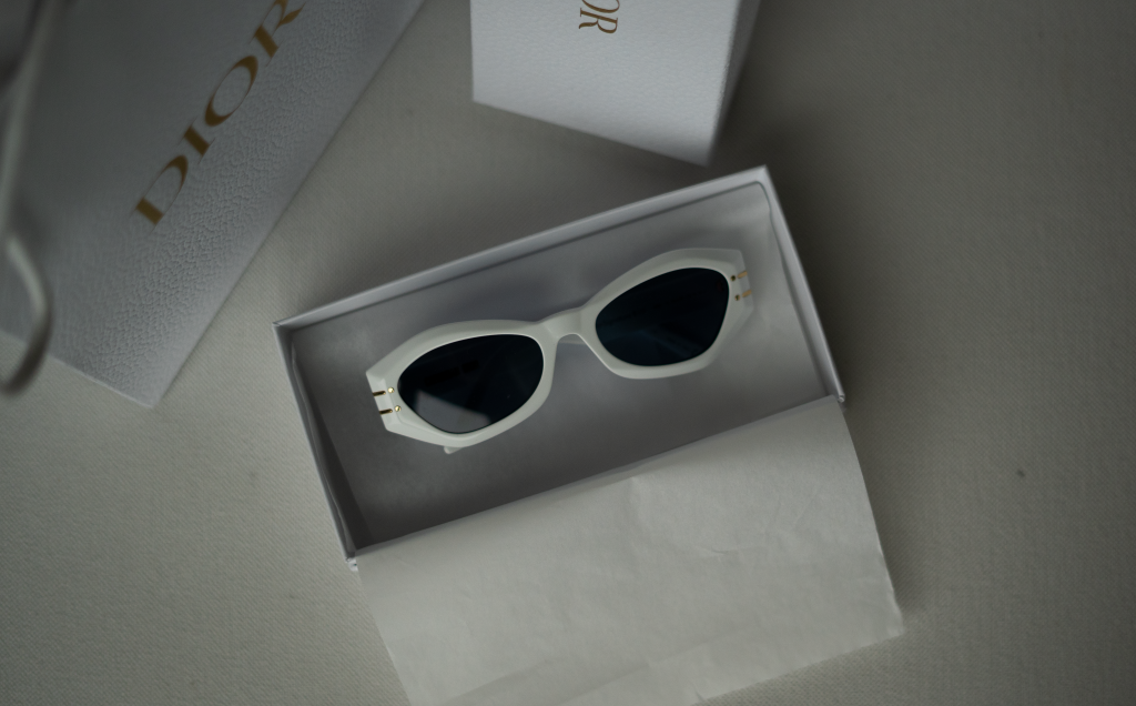 Chic Dior sunglasses in a sleek white frame, displayed in a luxury branded box.